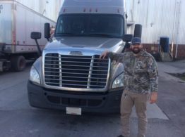 Man standing in front of semi truck smiling