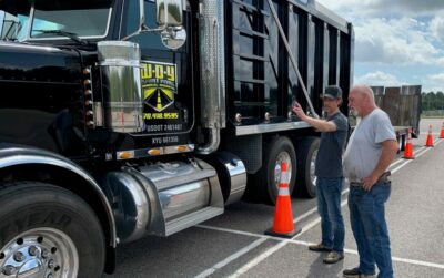 ELDT Traveling Provider instructing a man in front of a black dump truck