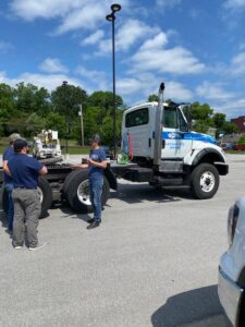 CDL trainer standing in front of a truck talking to two students